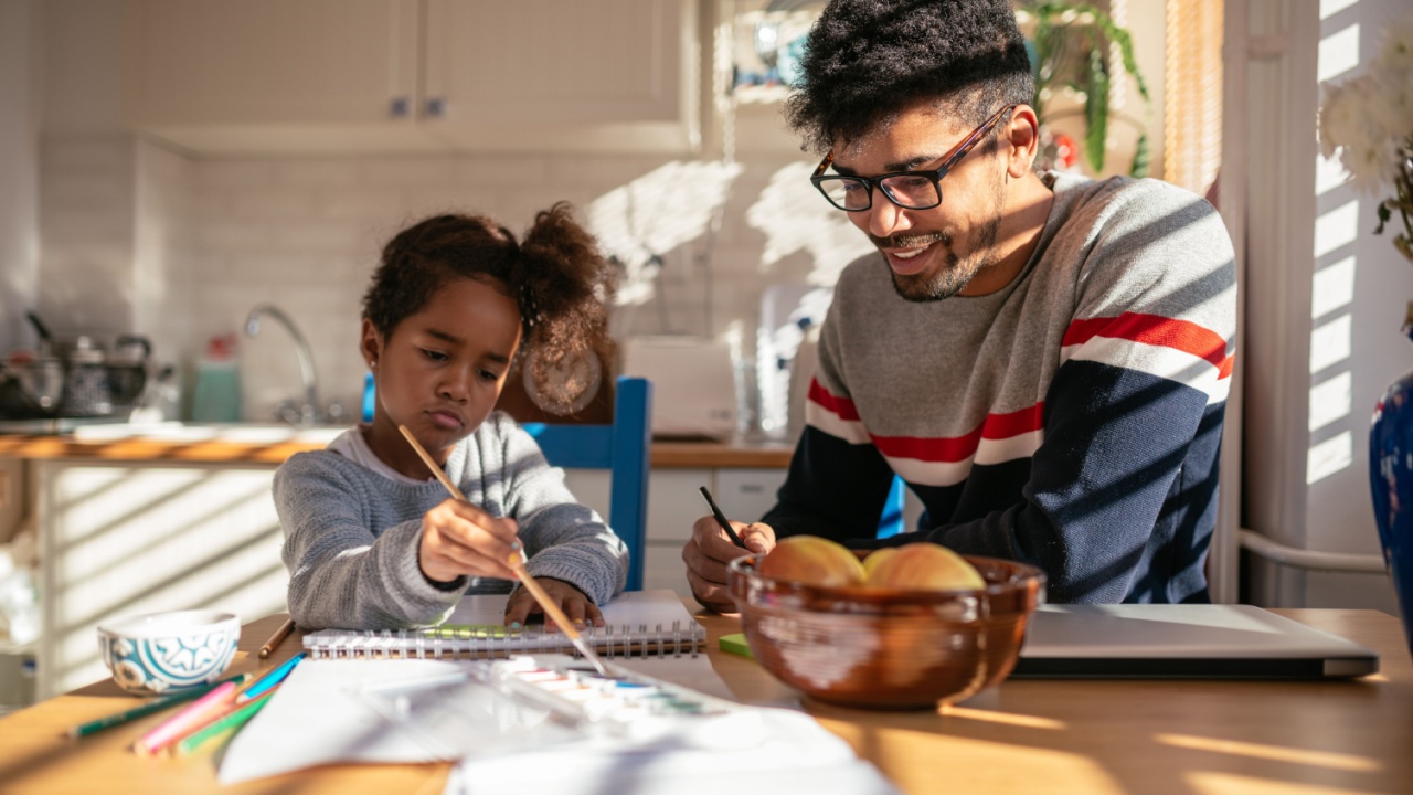 Man and daughter at table making art together.