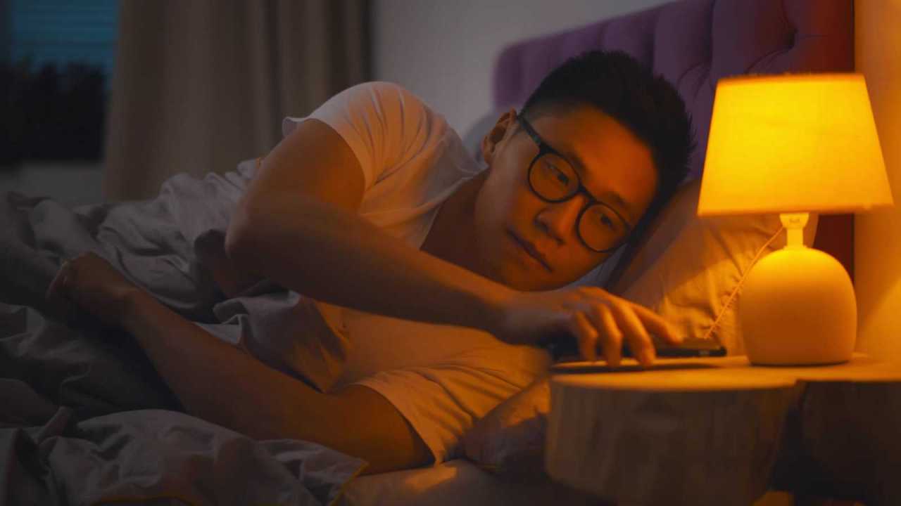 man about to turn off beside light to go to sleep.