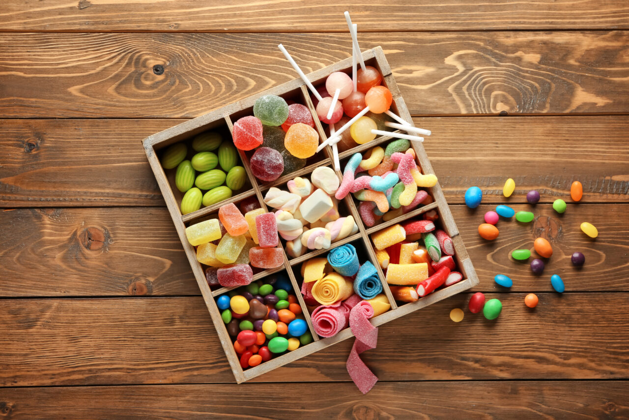 Box with different sweets on wooden background.