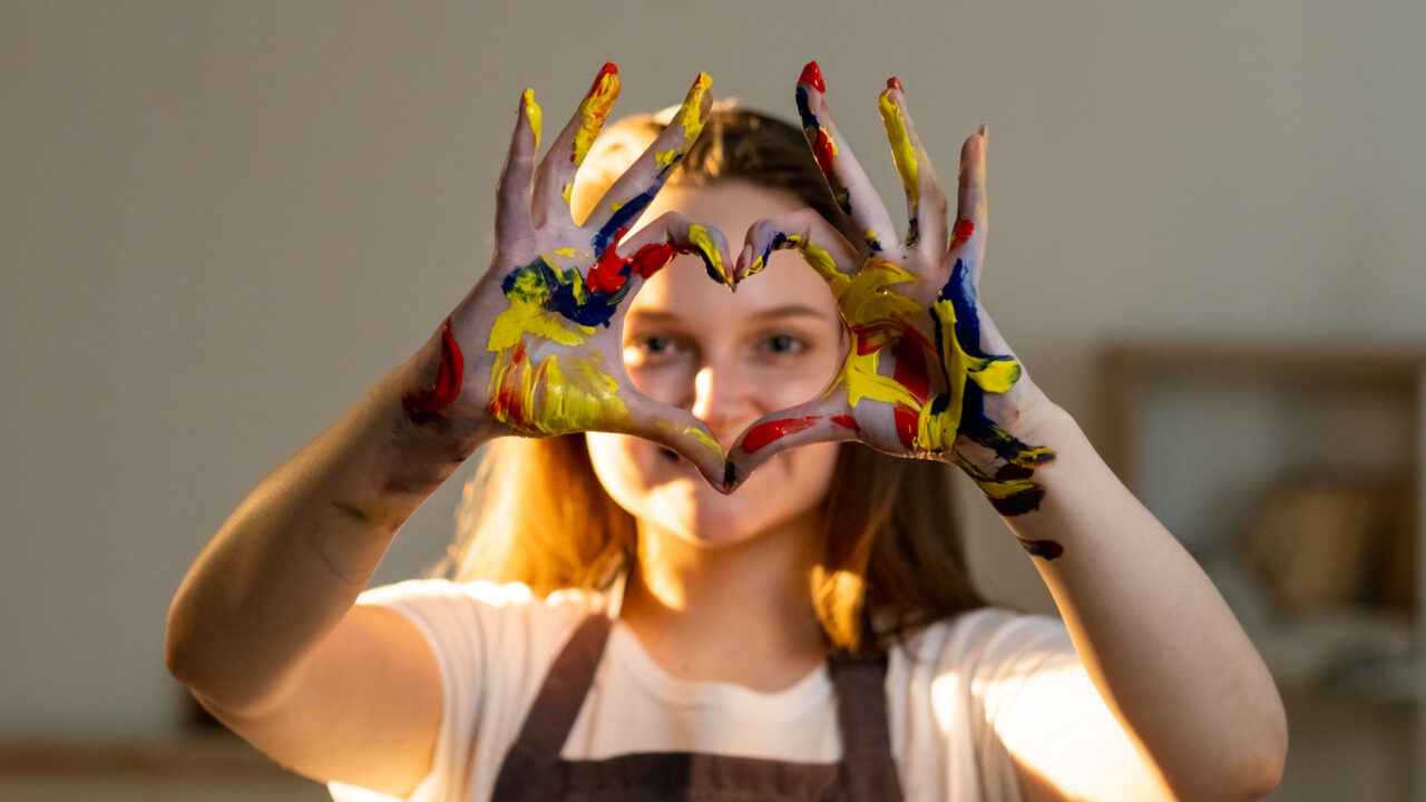 Painter making heart with paint stained hands.