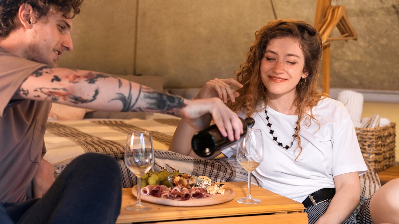 A happy couple resting in a tent with dinner.