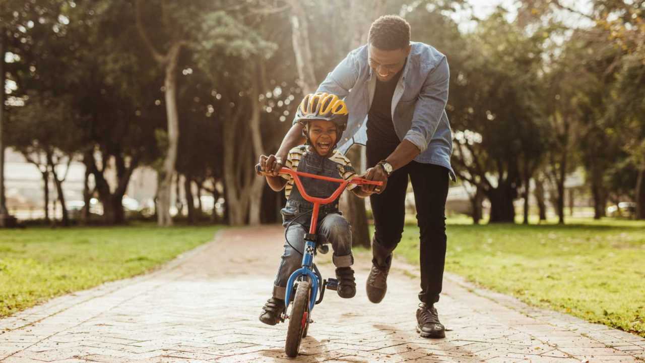 Dad teaching son to ride a bike.