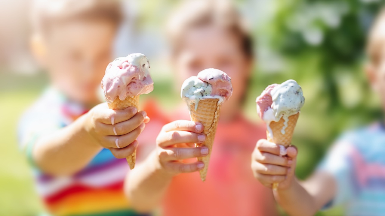 Group of three kids holding ice cream cones that are starting to melt and drip.