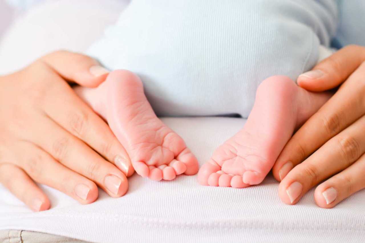 Adorable baby feet nest to moms hands.