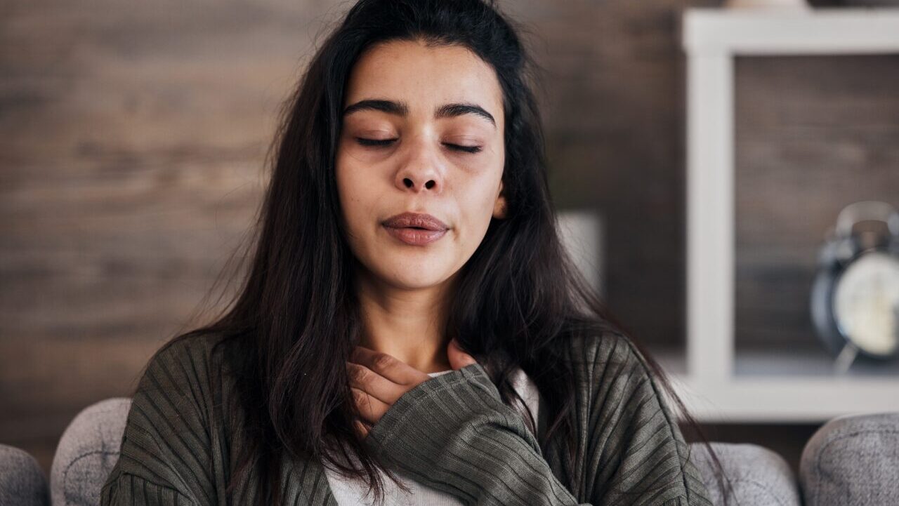 stressed woman on sofa in living room breathing deep and trying to calm down.